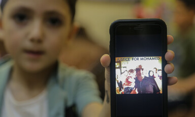 A boy holds a mobile phone with a picture of a man holding a baby