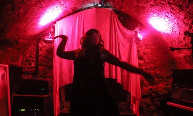 A dark silhouette against a red curtain of a person dancing