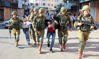 Armed soldiers detain two handcuffed men 