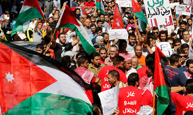 Crowd of dozens carry Jordanian flags, banners