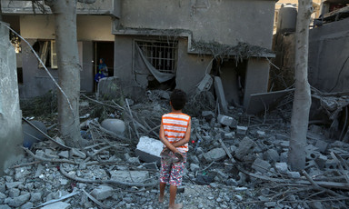 Back view of child looking at rubble of bombed-out building