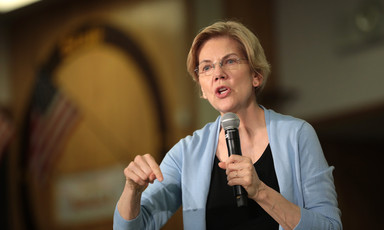 A woman holds a microphone and gestures