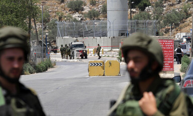 Soldiers stand n front of military tower and roadblocks