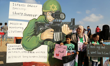 Woman and children stand in front of giant cut-out of soldier holding rifle
