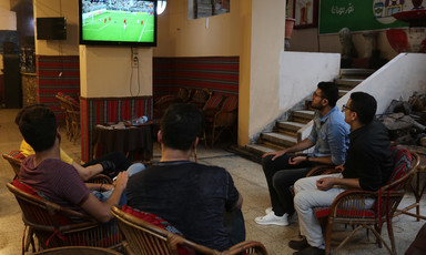 Five men watch football match on television