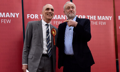 A man points at another man standing next to him