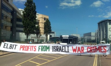Seven activists hold up a huge banner against Israeli war crimes