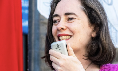 A woman speaks into a microphone attached to a megaphone