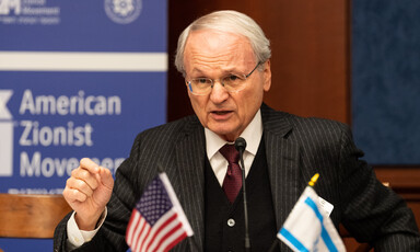 Man gesticulates behind Israeli and US flags