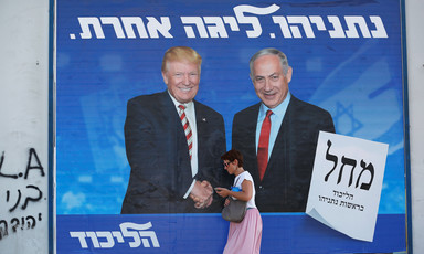 Woman walks past billboard of Trump and Netanyahu