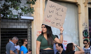 A woman holds up a sign with Arabic writing on it.