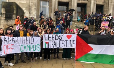 People holding signs and a Palestinian flag