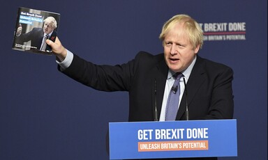 A man in a suit holds up a booklet