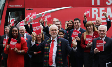 A group of people hold up a red booklet