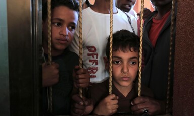 Two boys stare through bars in a window