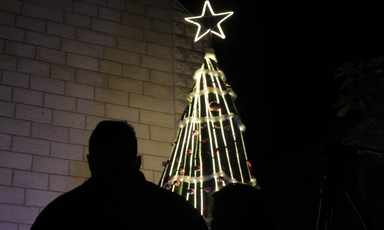 Silhouette of a man near a lit Christmas tree 