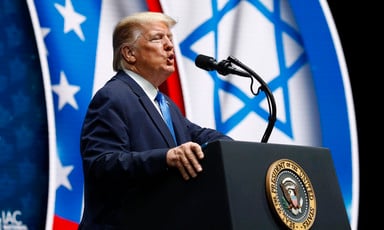 Man speaks at podium in front of Israeli and US flags