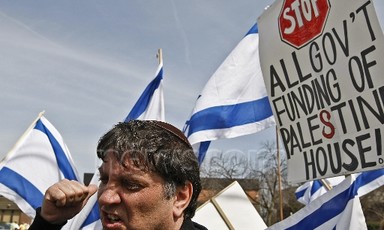 Meir Weinstein speaks as Israeli flags wave in background
