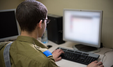 Man in military uniform sits in front of computer