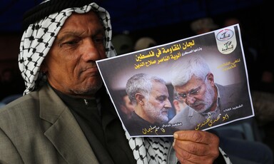 A man holds a picture of a slain Iranian general.