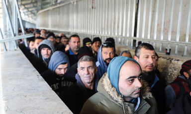 Men queue in a concrete walkway