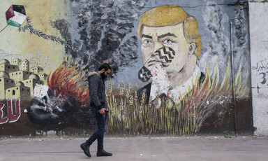 A man walks past a mural depicting US president Donald Trump with a footprint across his face