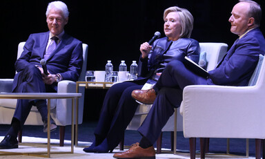 Three people talk on stage