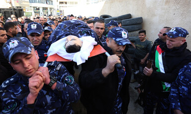 Men in camouflage uniform carry body on stretcher