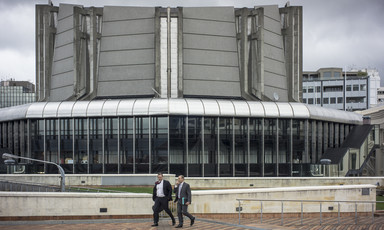 Two men walk in front of a modern building