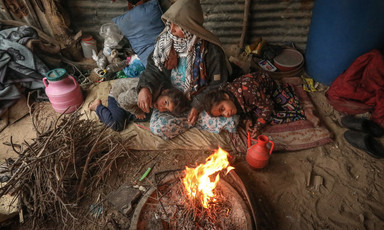 A woman and two children sitting near fire
