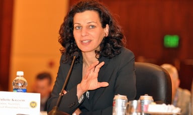 Woman in suit sits near microphone 