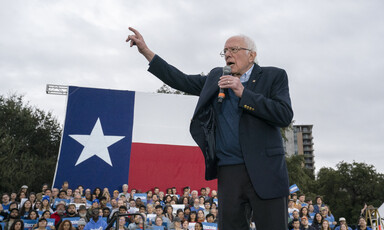 Man on podium speaks to crowd of supporters