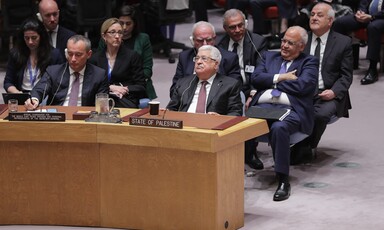 Several men, all in suits, sit behind a curved desk