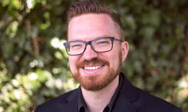 A man with a glasses and a beard smiles