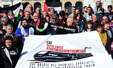 A large group of people holds a banner