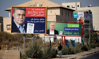 Two men are seen on two separate election posters in front of a house