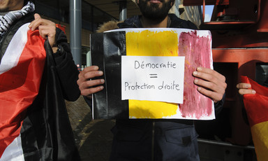 Man holds black, yellow and red placard 
