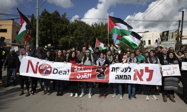 Demonstrators holding large banner, flags 