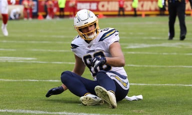 American football player sits on ground