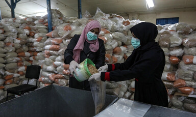 Women pour dry beans into bags