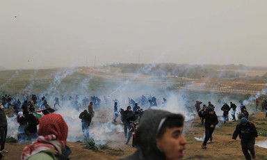 People in a field run amid streaks of smoke 
