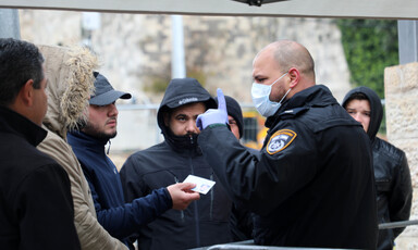 Uniformed man in protective face mask raises finger at group of men without masks