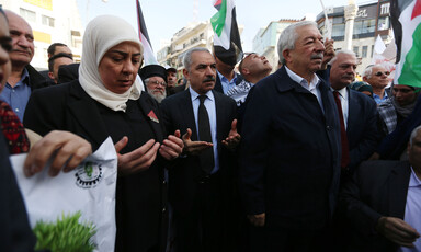 A crowd of people turn their palms upward in prayer