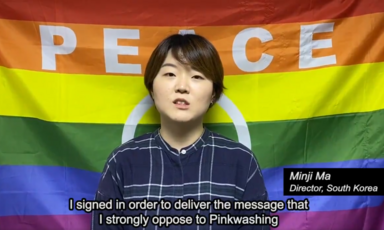 A woman stands in front of a rainbow flag