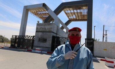 Many wearing protective gear stands near border gate