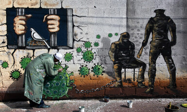 Man paints wall with images representing the virus and prisoners
