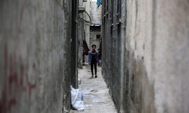 Walls tower over a child in a narrow passage
