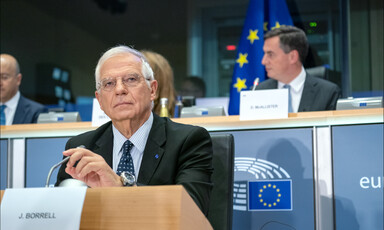 Man sits at podium touching microphone