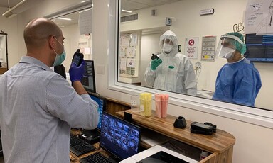 Men wearing masks hold electronic devices 