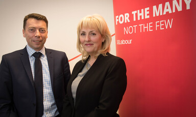 A woman and a man in suits pose and smile